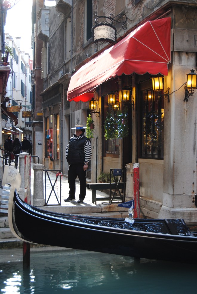 A gondolier taking a break, while watching his gondola.